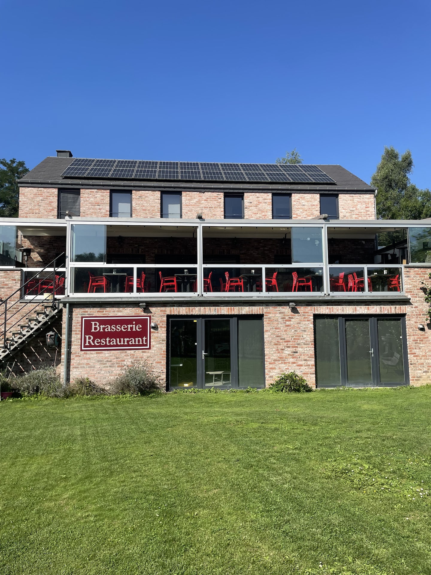 Restaurant avec terrasse et panneaux solaires en journée.