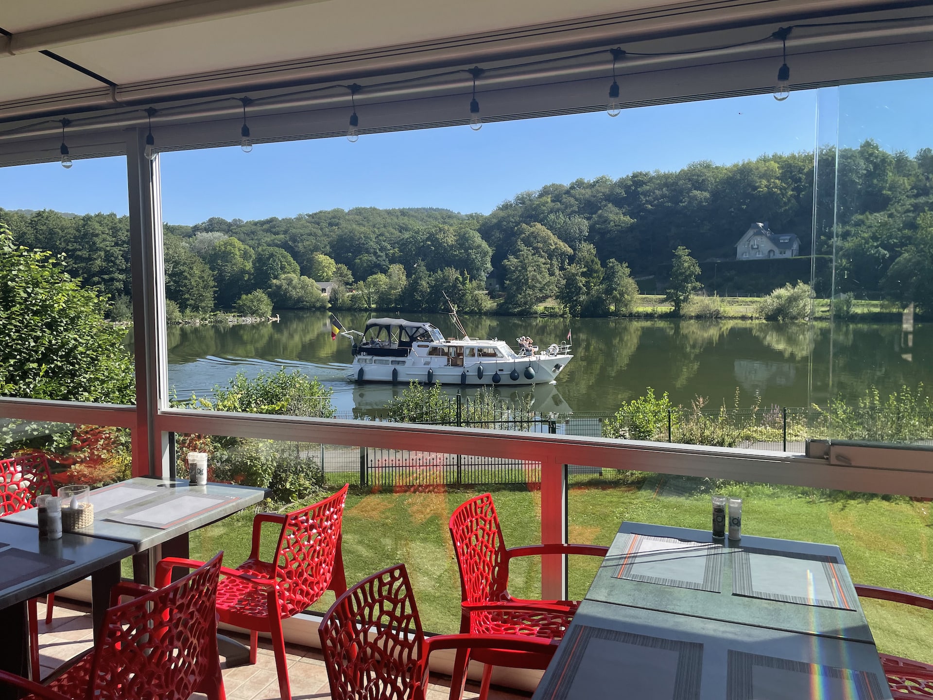 Terrasse de restaurant vue sur rivière et bateau.